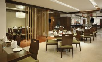 a dining area with several tables and chairs , as well as a buffet table with various food items at Four Points by Sheraton Ahmedabad