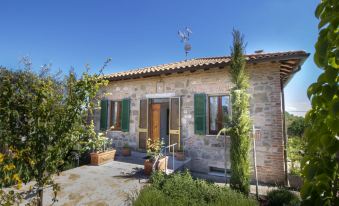 a small stone house surrounded by greenery , with a windmill in the background and a car parked nearby at Olimpia