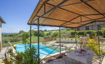 a patio with a wooden roof overlooks a pool and the surrounding landscape , including trees and bushes at Olimpia