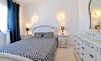 a white bedroom with a bed , dresser , and dresser lamps , giving it a cozy and inviting atmosphere at Esperanza