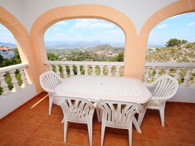 a white table and chairs are set up on a balcony with an arched window overlooking the outdoors at Joli Joli Photo