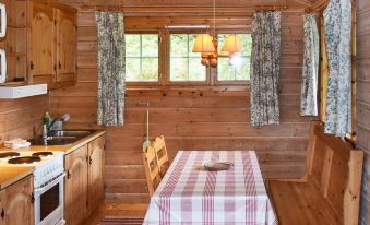 a cozy wooden cabin interior with a dining table , chairs , and kitchen appliances , all bathed in warm light at Olden