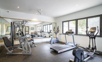 a well - equipped gym with various exercise equipment , including treadmills and weight machines , positioned near large windows at Beleza by the Beach