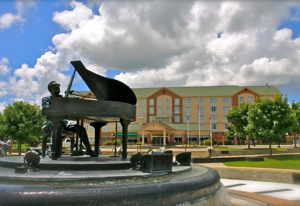 a fountain with a statue of a man playing a piano , located in front of a building at Hilton Garden Inn Albany