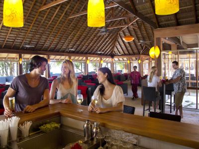 three women are standing at a counter in a restaurant , talking and enjoying their time at Vilamendhoo Island Resort & Spa