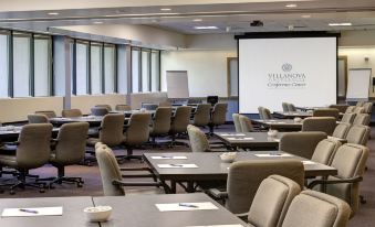 a conference room with rows of chairs arranged in a semicircle , and a projector mounted on the wall at Inn at Villanova University