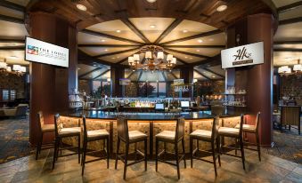 a bar with wooden ceiling , stone floor , and multiple stools arranged around the counter , as well as a chandelier hanging above at Lodge of Four Seasons Golf Resort, Marina & Spa