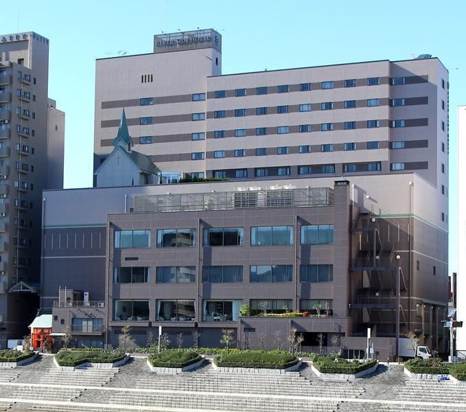 a large building with many windows and a building that has a spire on top at Numazu River Side Hotel