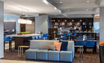 a modern hotel lobby with a gray couch , blue chairs , and a bar area , all decorated in a stylish manner at Courtyard Seattle Federal Way