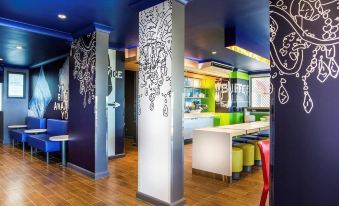 a modern restaurant with a dining area , featuring a variety of seating options and a colorful mural on the wall at Ibis Budget Brisbane Airport