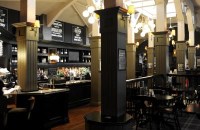 a bar with a large mirror and several bottles on display , creating an inviting atmosphere at Village Hotel Liverpool