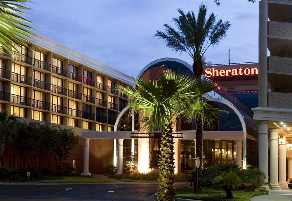 "a large hotel with a palm tree in front of it , and a building with the name "" sheraton ""." at Sheraton Orlando North Hotel