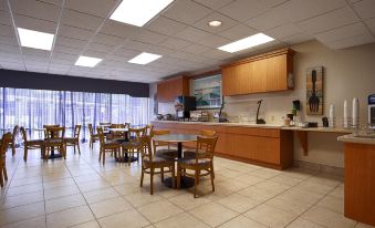 a large dining area with wooden tables and chairs , a kitchen counter , and large windows at Ramada by Wyndham Cocoa