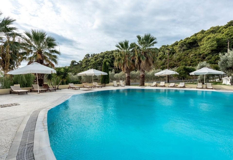 a large outdoor swimming pool surrounded by lounge chairs and umbrellas , providing a relaxing atmosphere at Belvedere Hotel