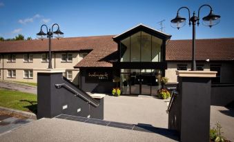 a modern building with a red roof and large windows , surrounded by black railings and potted plants at Gloucester Robinswood Hotel, BW Signature Collection