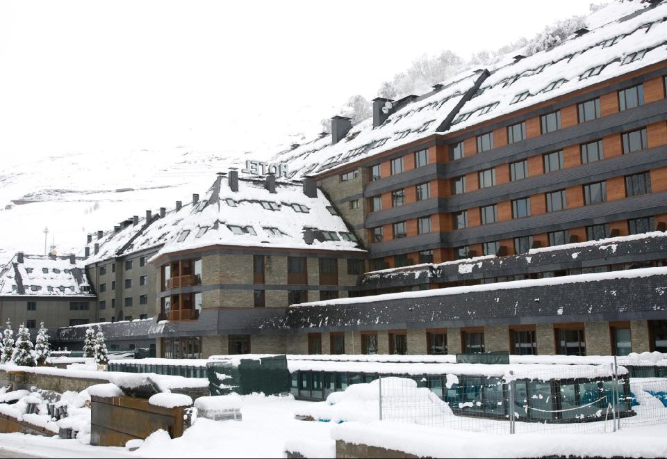 a snow - covered mountain with a large hotel building on top of it , surrounded by snow at Hotel Val de Neu G.L.