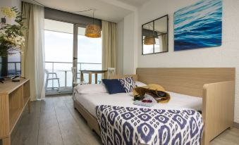 a bedroom with a large bed , white walls , and a sliding glass door leading to a balcony at Pierre & Vacances Blanes Playa