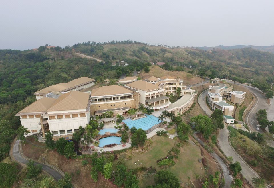 aerial view of a resort with multiple buildings , swimming pools , and lush greenery on a hillside at Timberland Highlands Resort