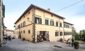 a yellow building with green shutters and a few signs in front of it , located on a street at Palazzo Leopoldo Dimora Storica & Spa