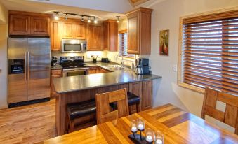 a kitchen with wooden cabinets , a stainless steel refrigerator , and a dining table with chairs at Wilderness Resort Villas