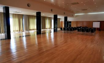 a large , empty room with wooden floors and high ceilings , surrounded by white walls and large windows at Hotel Colombo