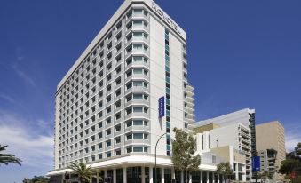 a tall , white building with many windows and balconies , situated in front of a street at Novotel Perth Langley