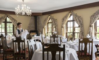 a restaurant with tables set up for dining , and a chef preparing the dining area at Abbeyglen Castle Hotel
