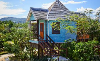 a wooden house with a blue exterior and a red roof is surrounded by lush greenery at GoldenEye