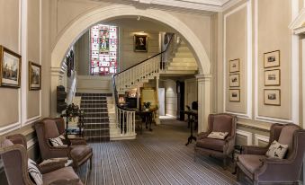 a spacious foyer with multiple couches and chairs arranged for guests to sit and relax at Eshott Hall