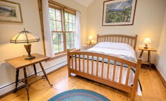 a cozy bedroom with hardwood floors , a wooden bed , and a rug on the floor at Blueberry Hill Inn