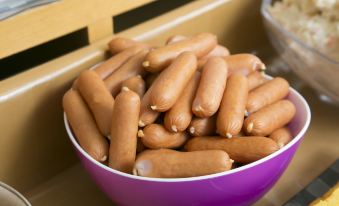 a purple bowl filled with a large number of hot dogs is placed on a table at Ace Inn Matsumoto