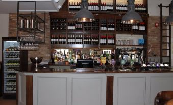 a bar with a variety of wine bottles and bottles on the wall behind it at The Woolpack Inn