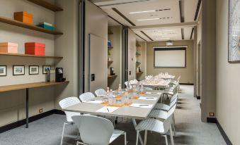 a conference room with a long table and white chairs , set up for an event at Room Mate Giulia
