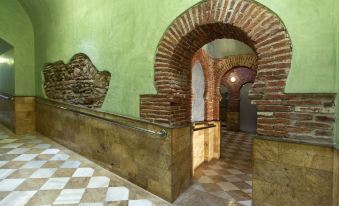 a room with a green wall and an archway , featuring a checkered floor and stone walls at Hotel Balneario de Graena
