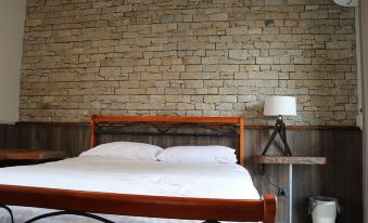 a bed with white sheets and a wooden headboard is next to a nightstand with a lamp at Hampton Halfway Hotel Motel