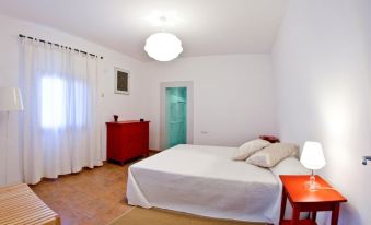 a white bedroom with a red bed , a red dresser , and a large mirror on the wall at Casa Amigos