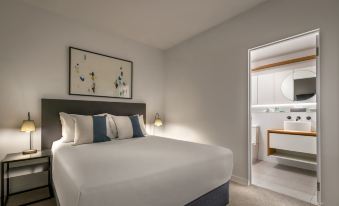 a large bed with white linens is in a room with a painting on the wall and a light switch at Punthill Ivanhoe