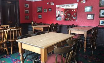 a room with a wooden table and chairs , a mirror on the wall , and red walls at Cross Keys