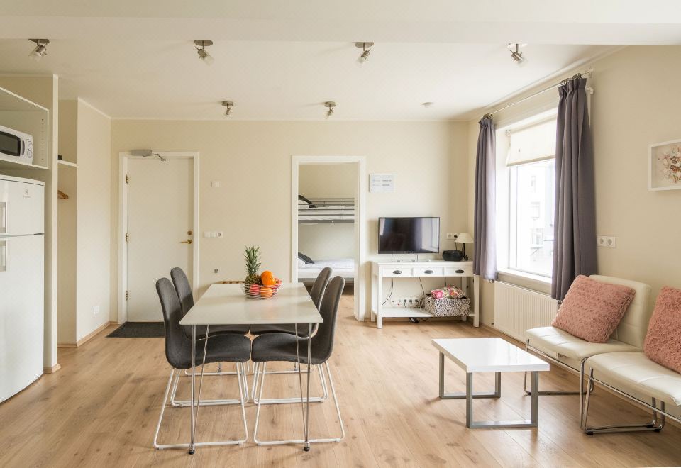 a living room with a dining table and chairs , a television , and a bedroom in the background at Acco Town Square Apartments