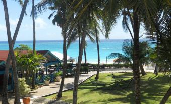 a beautiful tropical beach with palm trees , blue water , and white sandy beaches , under a sunny sky at Bougainvillea Barbados