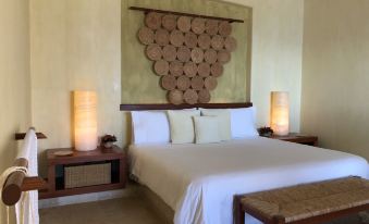 a large bed with white linens and a wooden headboard is in a room with two lamps at Cala de Mar Resort & Spa Ixtapa