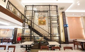 a restaurant with a dining area and a staircase leading to the second floor , where a painting is displayed at Villa Baron