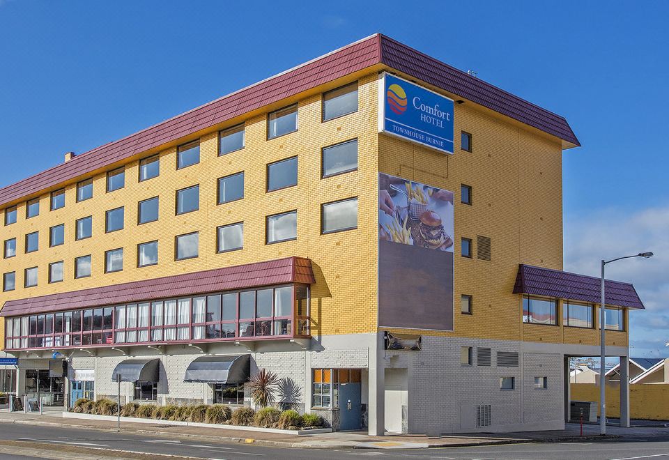 a tall yellow building with a sign on the side , situated in a city setting at Burnie Central Townhouse Hotel