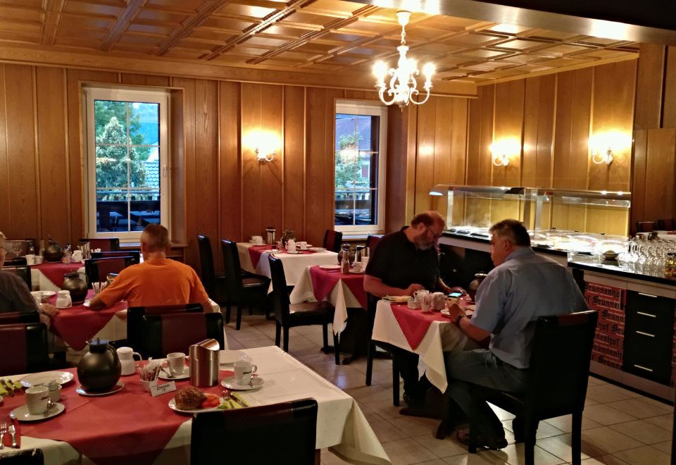 a group of people sitting at dining tables in a restaurant , enjoying their meal together at Hotel Brunnenhof