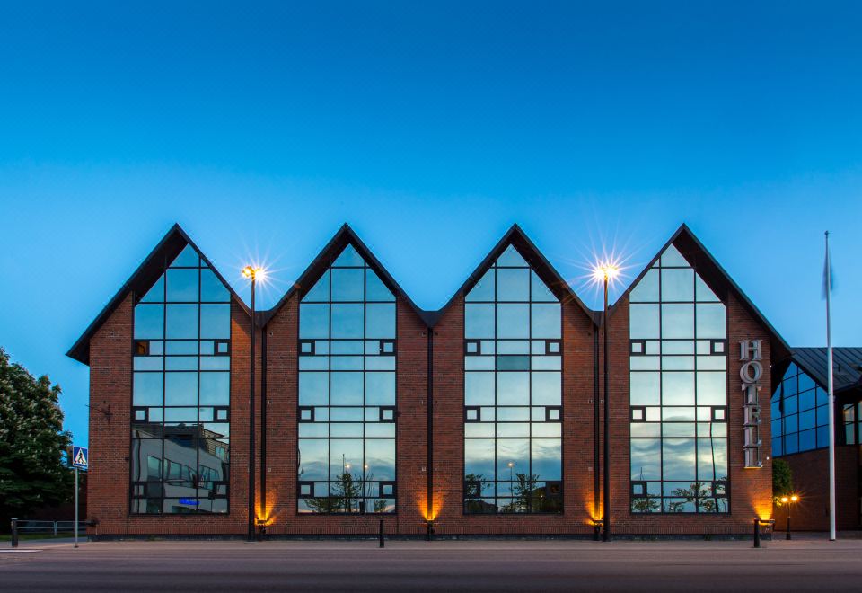 a modern building with a triangular shape and large windows is lit up at night at Clarion Collection Hotel Carlscrona