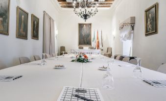 a large white table with a black and white tablecloth , surrounded by chairs , in a room with a chandelier at Parador de Zafra