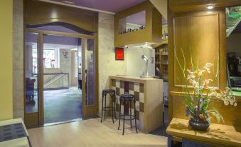 a modern , well - lit room with wooden floors and walls , featuring a bar area with stools and a vase of flowers at Hotel Gran Via