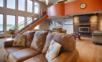 a large living room with a brown leather couch and a staircase leading to the second floor at Best Western Park Oasis Inn