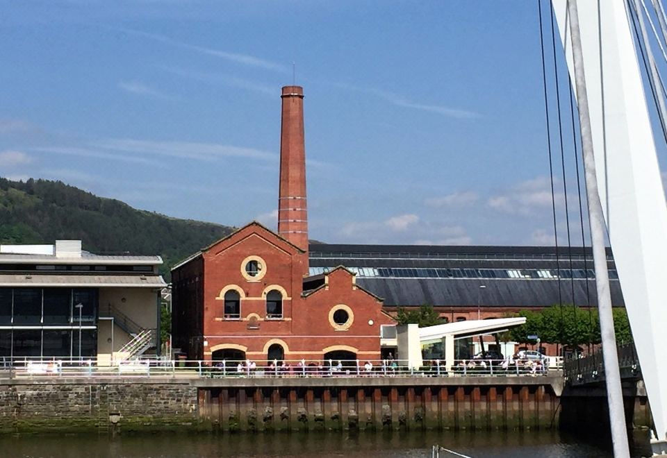 a red brick building with a chimney is situated next to a body of water at Ice House Apartments