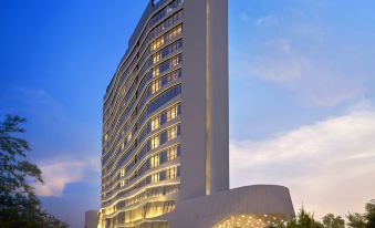 "a tall white building with a curved design and a sign that reads "" fahrenheit 2 5 "" in front of it" at DoubleTree by Hilton Ahmedabad